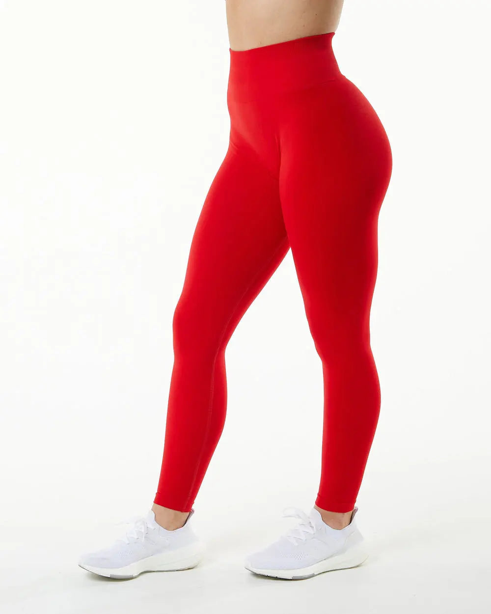Une personne portant des leggings de yoga rouges sans couture taille haute et des baskets blanches.