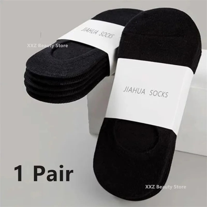 A pair of black invisible silicone no-show boat socks with white branding displayed on a white background.