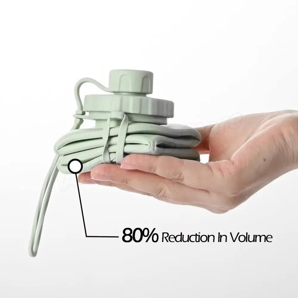 Una mano sostiene una botella de agua de silicona plegable verde claro, demostrando una reducción del 80% en el volumen.