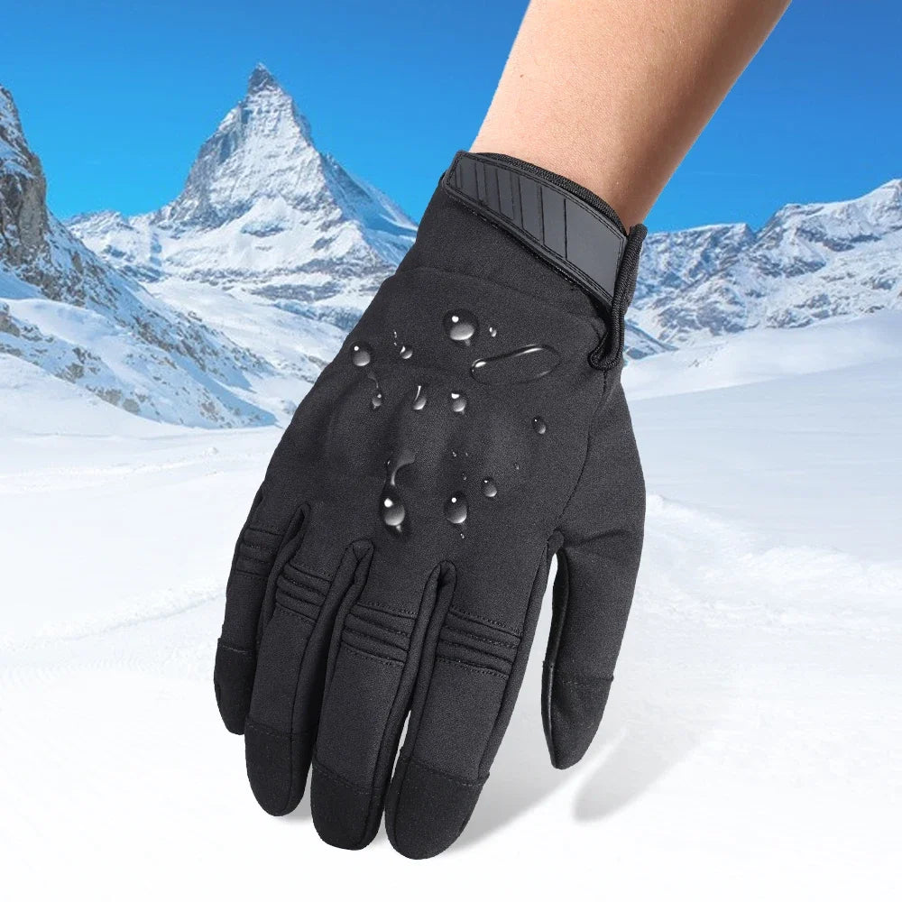 A close-up of black motorcycle riding gloves being held against a snowy mountain backdrop.