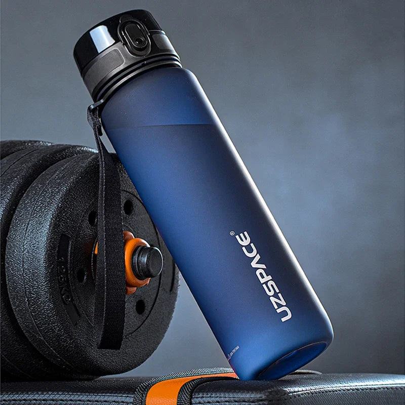 Blaue wiederverwendbare Sportflasche mit schwarzem Tragegurt vor grauem Hintergrund.