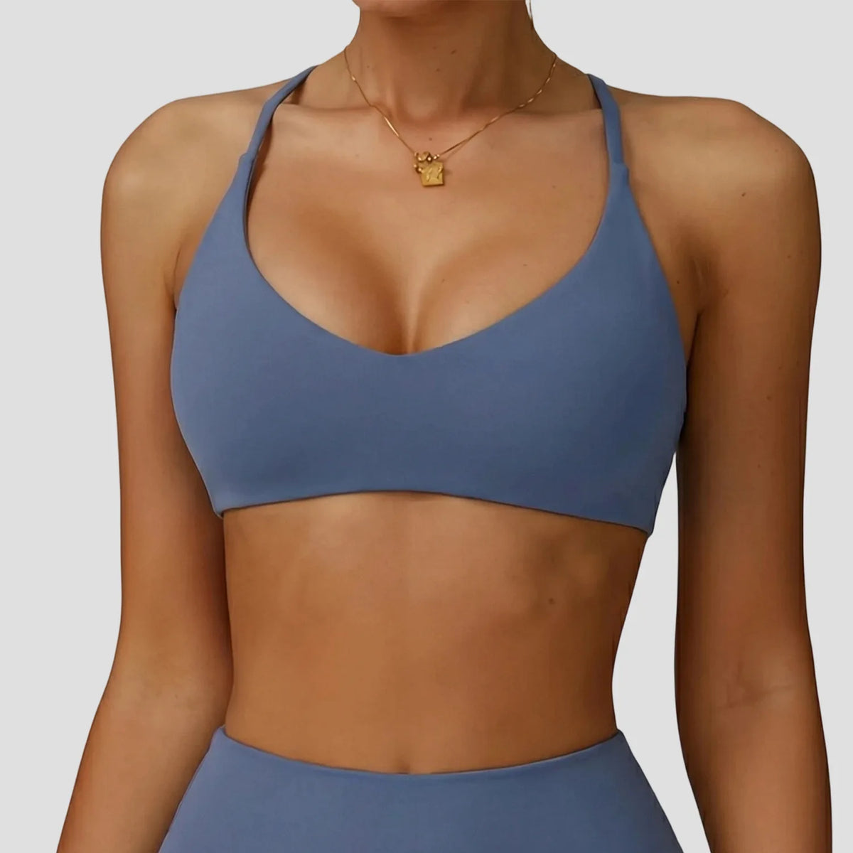 A woman wearing a solid blue high-support sports bra for yoga and fitness.