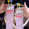 Pair of purple knit socks with embroidered cartoon faces and yellow and blue hair-like accents.