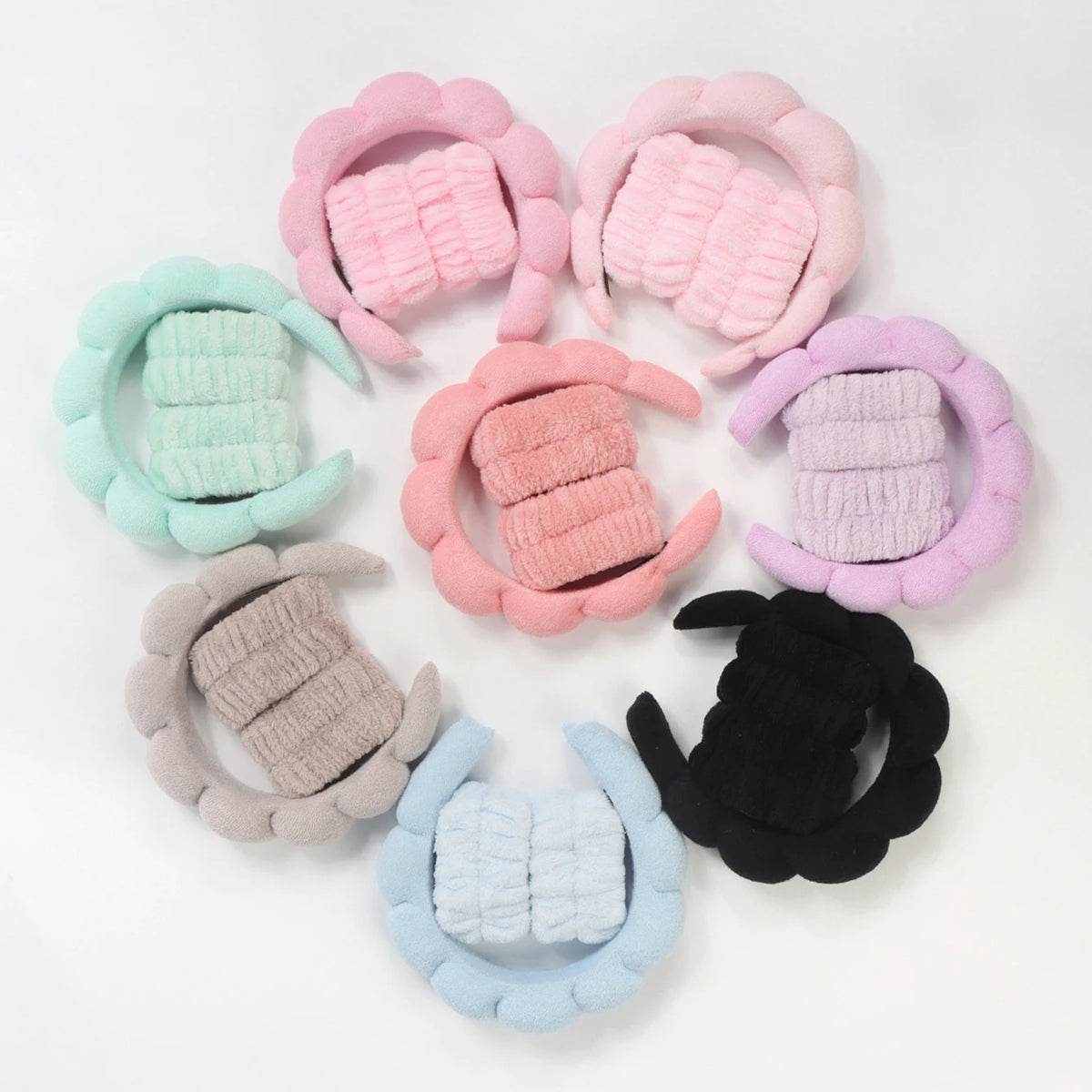 A set of pink, mint green, purple, and black microfiber skincare headbands and wristbands.