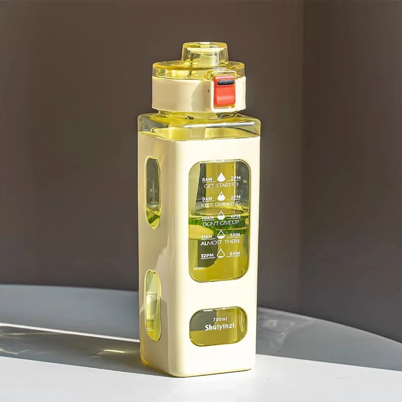 Klare Glasflasche mit gelblicher Flüssigkeit, weißem Verschluss und Strohhalm auf einer hellen Oberfläche.