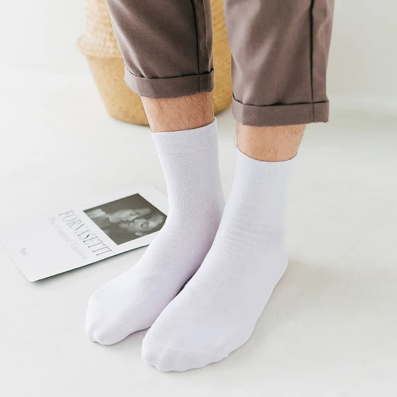 Une paire de chaussettes blanches à col sont portées par une personne, avec un pantalon marron visible.