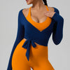 A woman wearing a blue long sleeve top and matching orange leggings