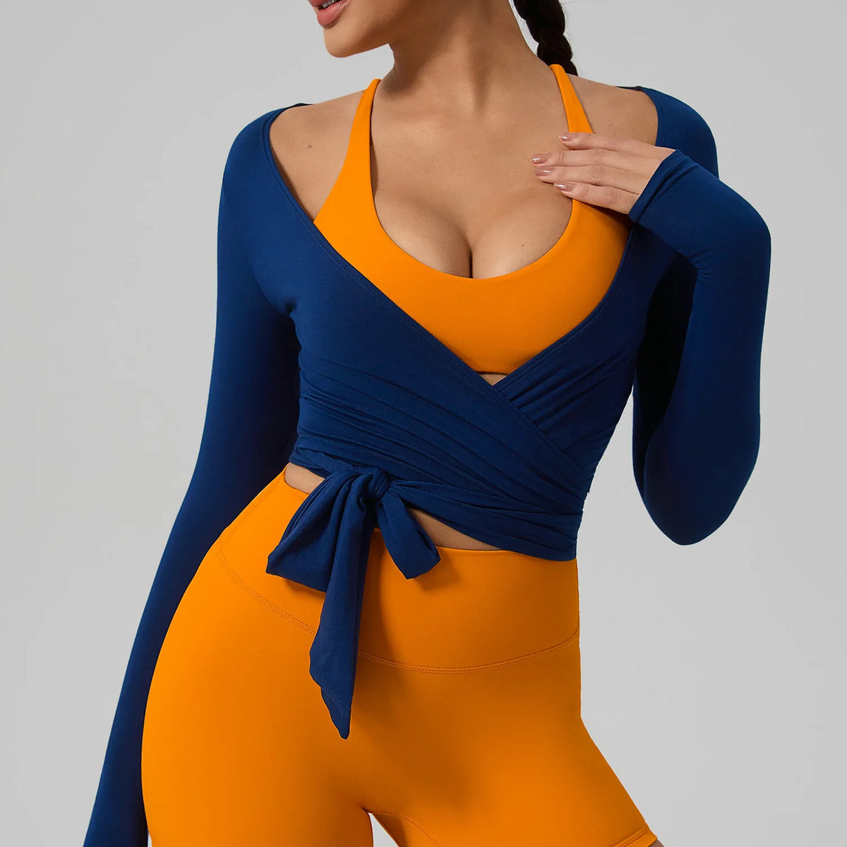 A woman wearing a blue long sleeve top and matching orange leggings