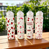 Four white tumblers with red strawberry and cherry designs are lined up on a wooden table.