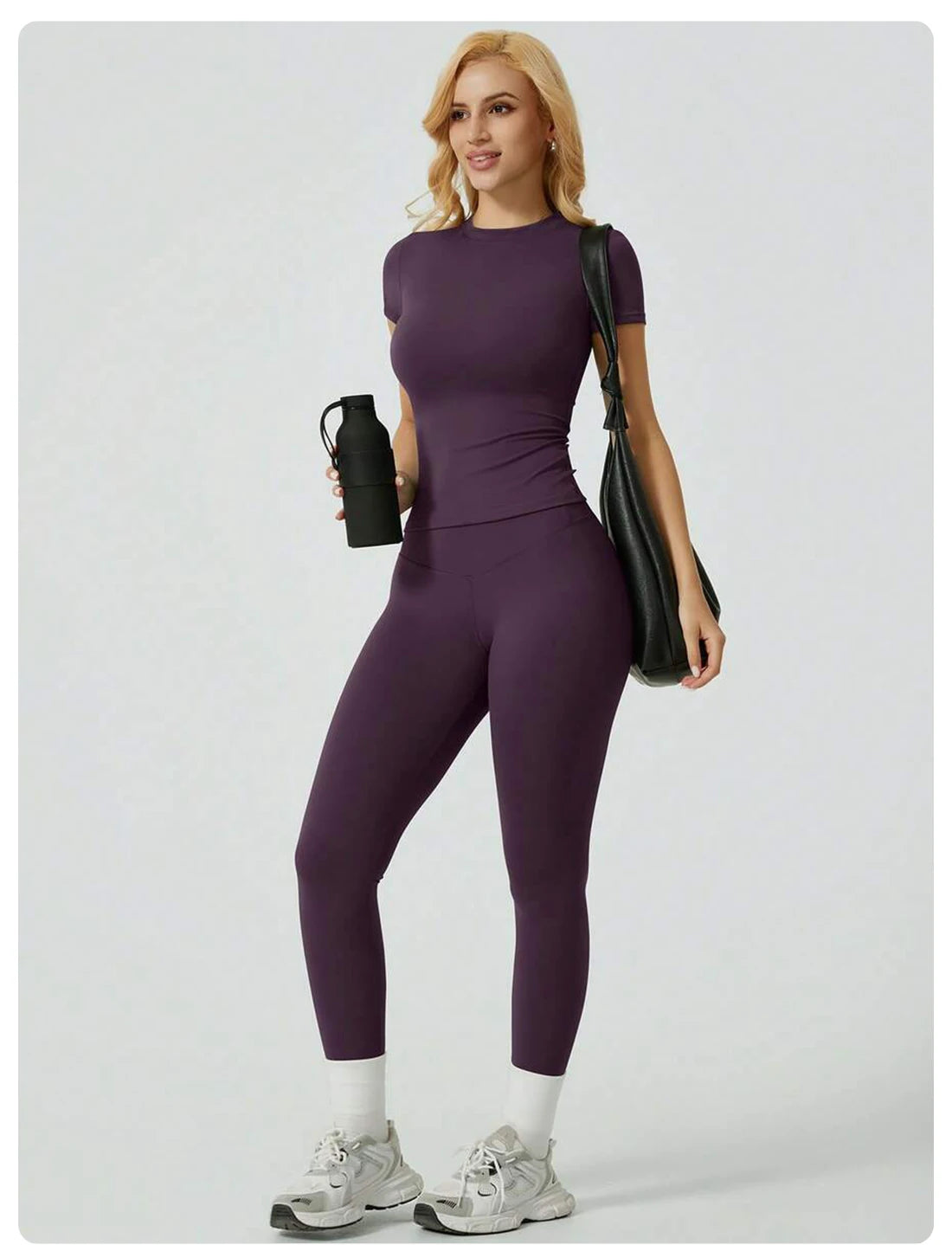 Eine Frau modelliert ein lila Zweiteiler-Yoga-Set mit hohen Bund-Leggings und einem kurzärmeligen Oberteil mit schwarzem Träg