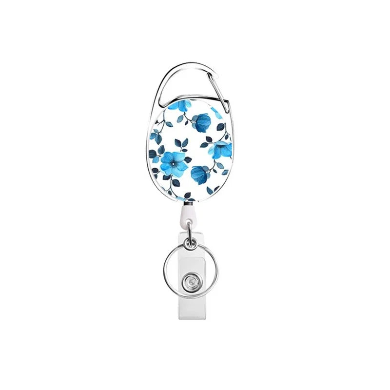 A blue floral patterned retractable ID badge reel keychain with a silver clasp.