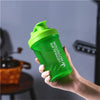 A hand holds a bright green leakproof protein shaker bottle against a gray background.