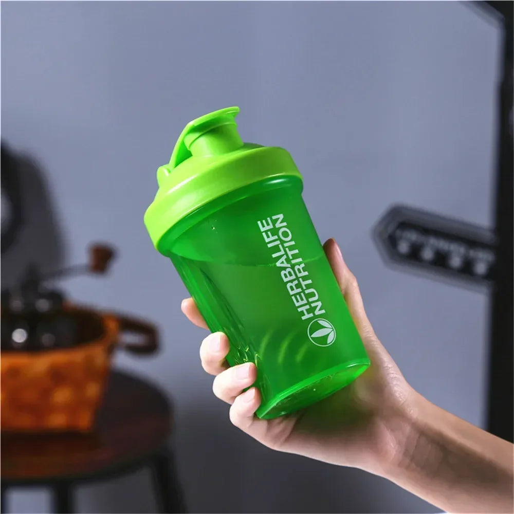 A hand holds a bright green leakproof protein shaker bottle against a gray background.