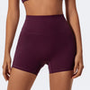A model is wearing a deep purple high-waist yoga and workout short for exercise.