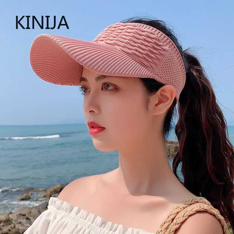 A woman wearing a pink breathable anti-UV adjustable sun hat outdoors near the sea.