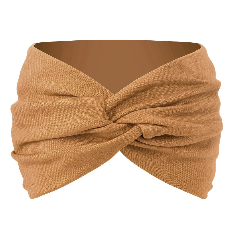 A beige twisted criss cross elastic headband for yoga and sports.