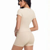 A woman models a beige women's performance 2-piece workout set top and shorts.