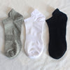 Dreipack aus grauen, weißen und schwarzen Knöchelsocken auf weißem Untergrund.