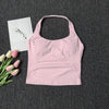 A light pink seamless yoga and pilates sports bra is displayed on a dark gray fabric next to pink and white tulips.