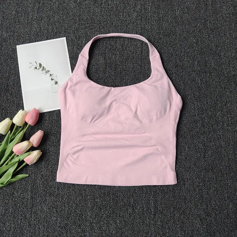 A light pink seamless yoga and pilates sports bra is displayed on a dark gray fabric next to pink and white tulips.