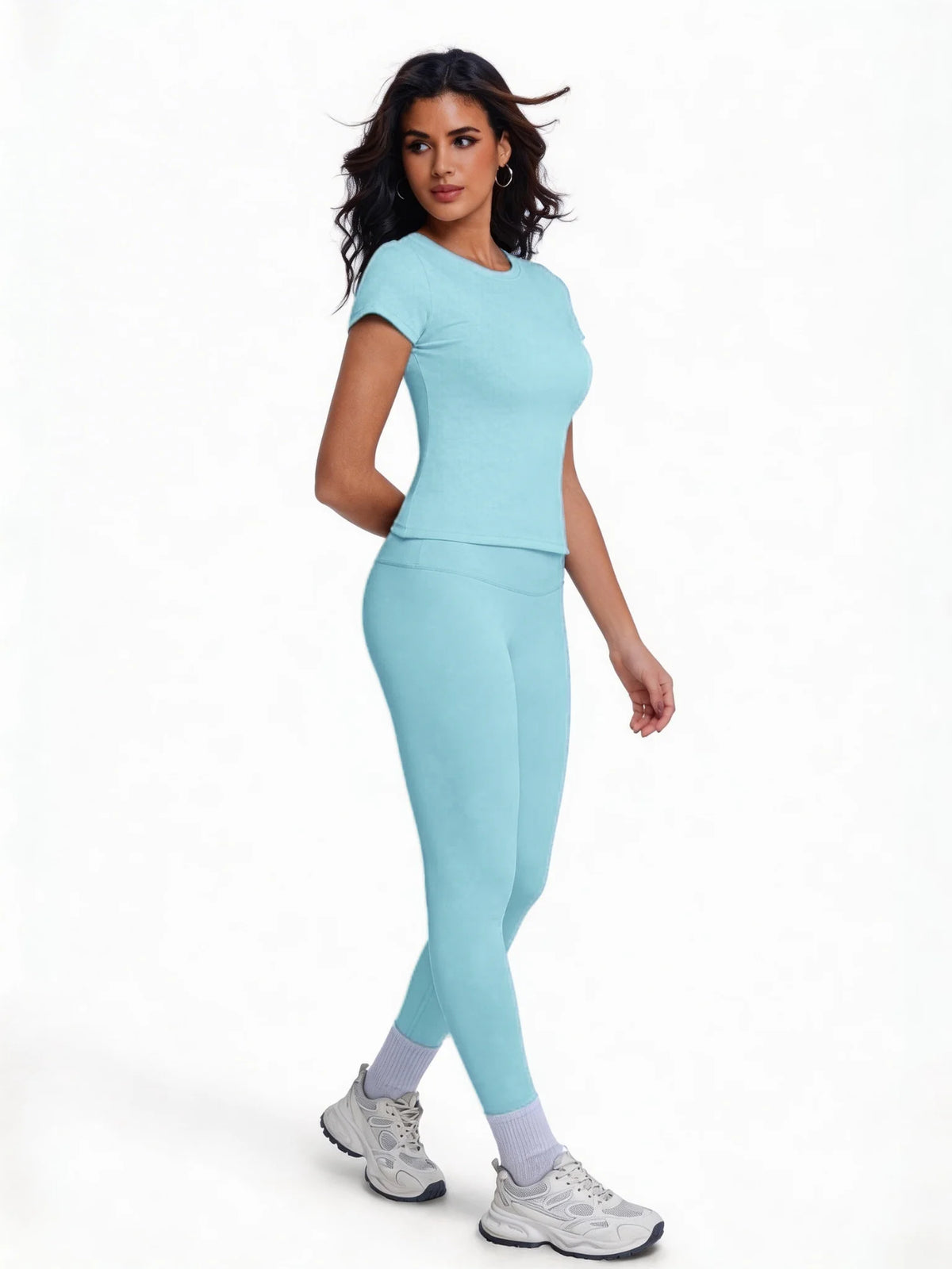 Una mujer modela un conjunto de yoga sin costuras, de cintura alta y color azul claro, con top de manga corta y leggings.
