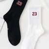 A pair of black and white crew socks featuring the number 23 on the foot.