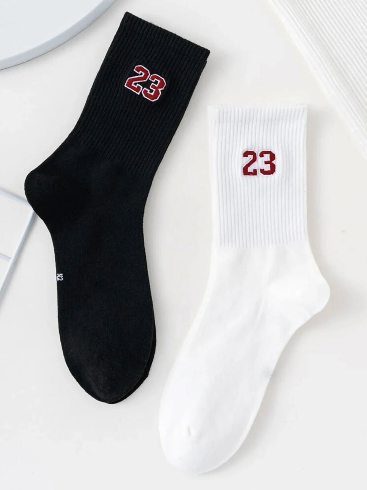 A pair of black and white crew socks featuring the number 23 on the foot.