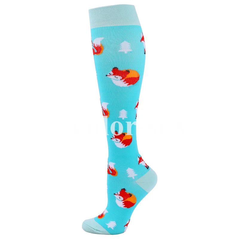 A pair of light blue compression socks featuring a repeating pattern of orange and white reindeer.