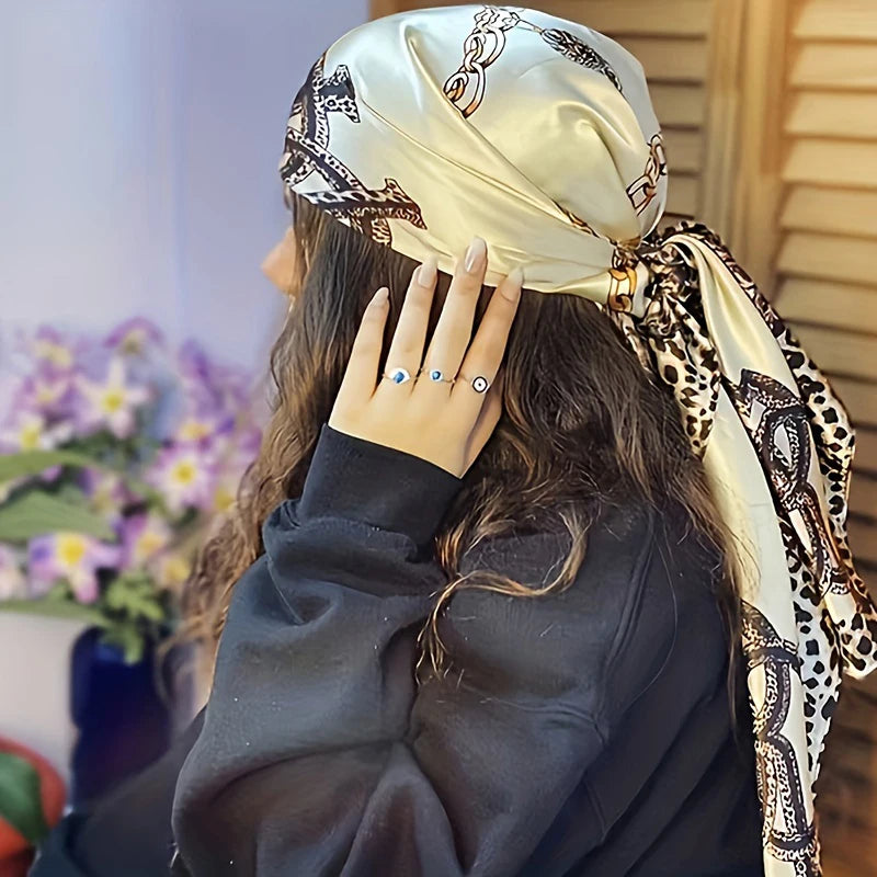 A woman wearing an elegant satin square scarf for hijab and hair, featuring a black and white leopard print.
