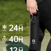 A black insulated sports water bottle with a magnetic lid is held by a person outdoors.