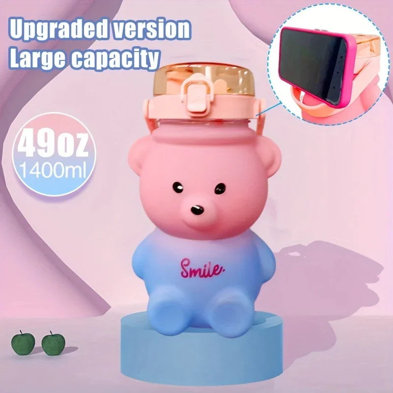 A pink bear-shaped water bottle with a straw and strap is displayed on a blue stand.