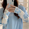 A woman is wearing light blue long-sleeved sun protection arm sleeves with a white floral pattern.