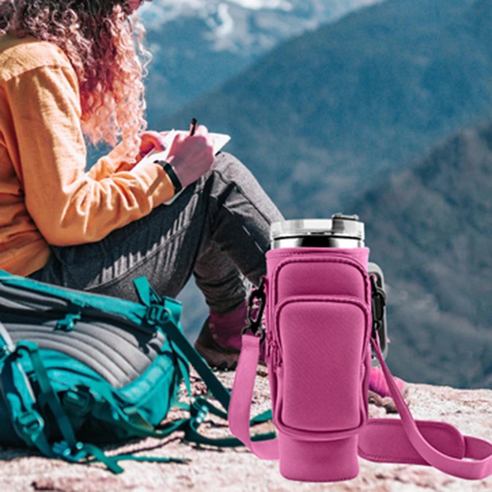 Pinkes Wasserflaschen-Tragetasche neben einer Person, die draußen schreibt mit einem Rucksack im Hintergrund.