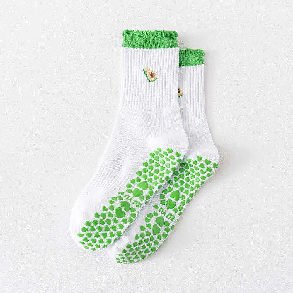 Ein Paar weiße Strick-Yoga- und Fitnesssocken mit grünem Zier und einem Muster aus grünen Herzen auf der Sohle.