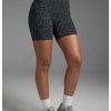 Une femme portant des shorts de yoga à taille haute à imprimé léopard et des baskets grises.