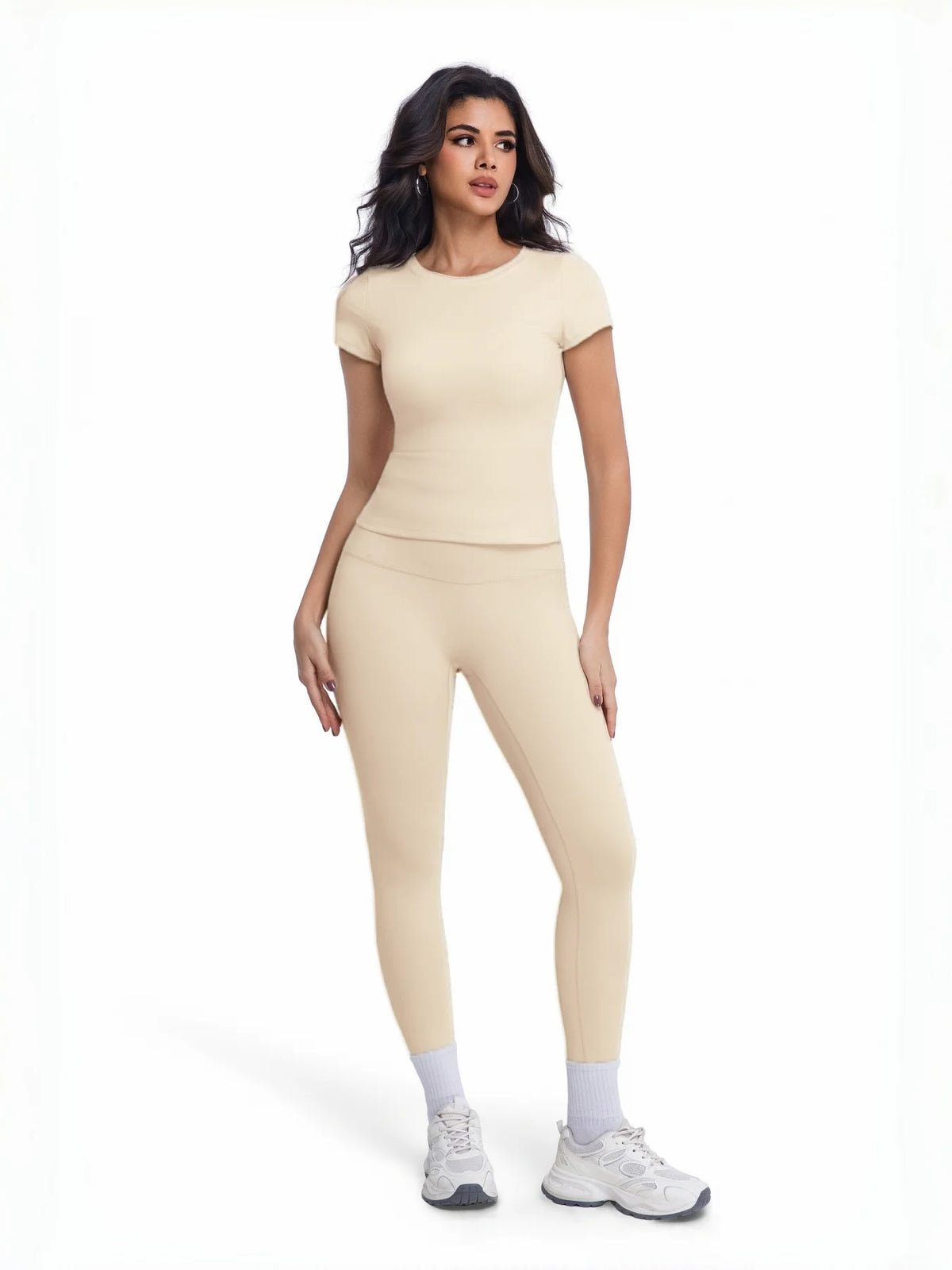 Una mujer modela un conjunto de yoga sin costuras de cintura alta en beige, que consiste en una blusa de manga corta y pantal