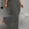 A woman wearing gray flared yoga trousers and a white shoulder bag.
