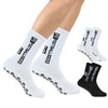 A pair of white men's athletic soccer socks with non-slip grip and black accents are displayed on a person's leg.
