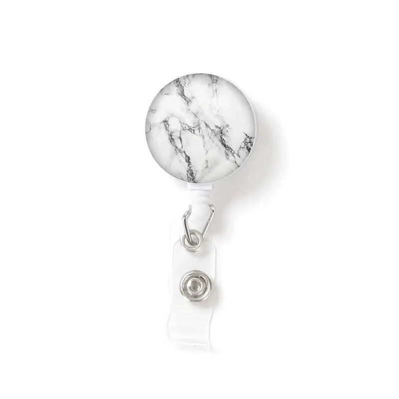 A round, white and gray marble-patterned ID badge is attached to a clear keychain.