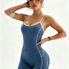 Eine Frau modelliert einen dunkelblauen, nahtlosen Yoga-Jumpsuit mit weißer Bordüre.