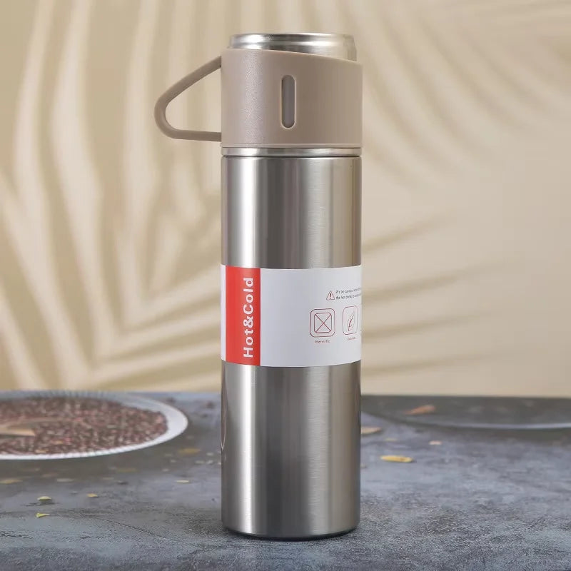 A silver stainless steel vacuum flask with a beige handle and red Hot&Cold markings sits on a dark surface.