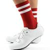 A close-up of a person's leg wearing red and white striped cycling socks and white athletic shoes.