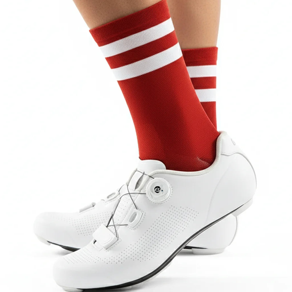 A close-up of a person's leg wearing red and white striped cycling socks and white athletic shoes.
