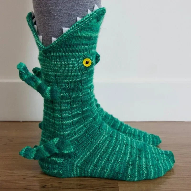 A green knit sock shaped like a crocodile with a yellow eye