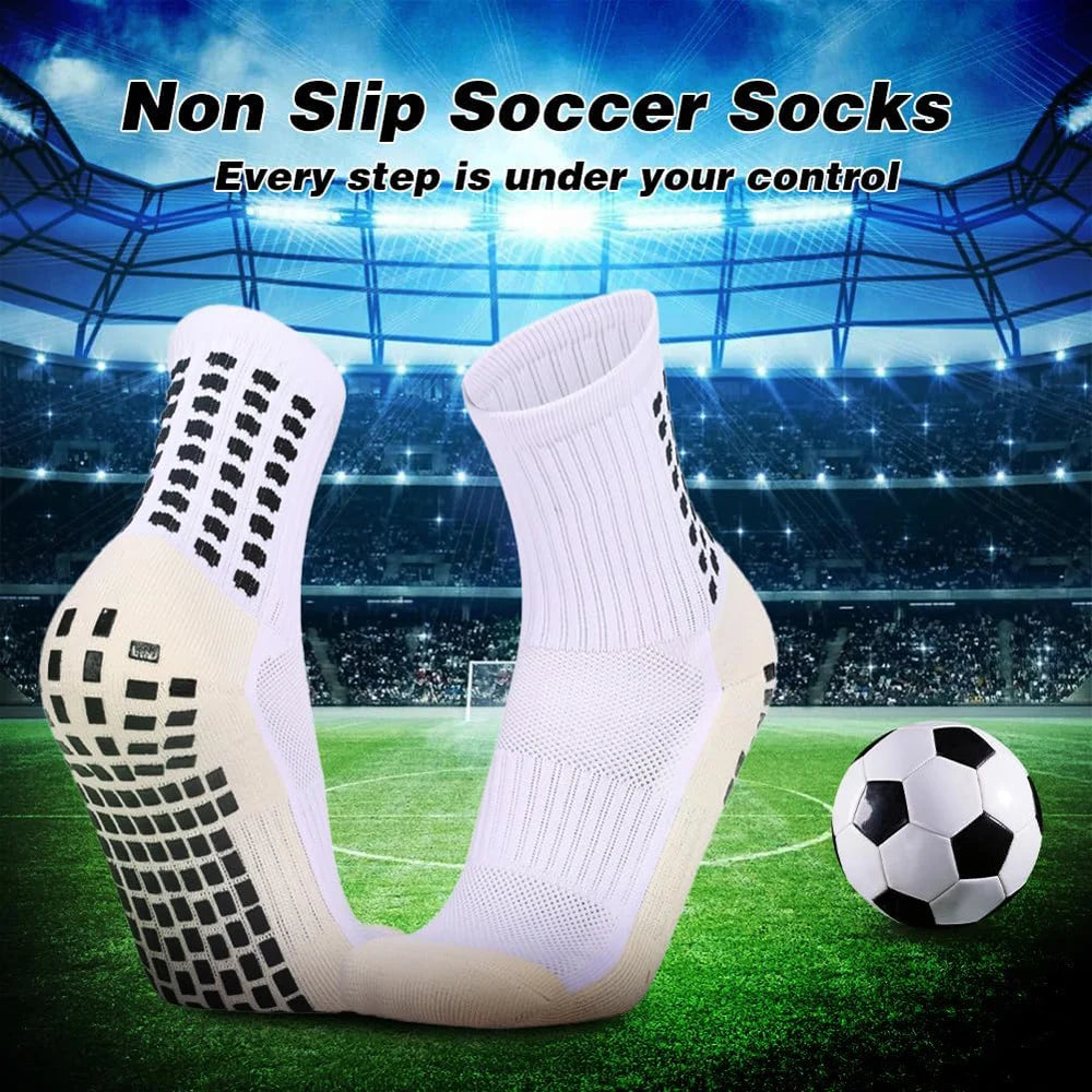 Ein Paar weiße rutschfeste Silikon-Fußballsocken auf einem grünen Feld mit einem Fußball daneben.