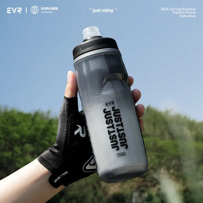 Una mano sostiene una botella de agua aislada EVR Just Riding al aire libre contra un fondo verde.