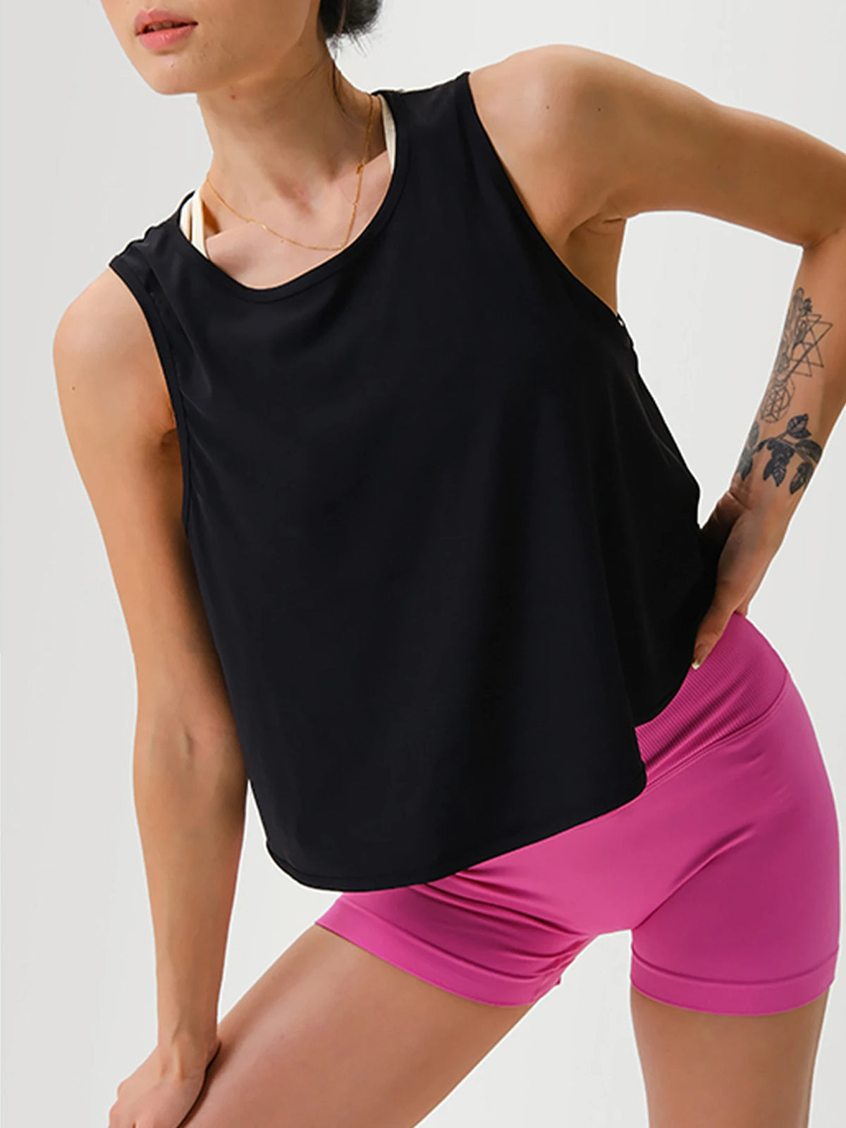 Model trägt ein schwarzes, nahtloses Crop-Top und pinke Sportshorts.
