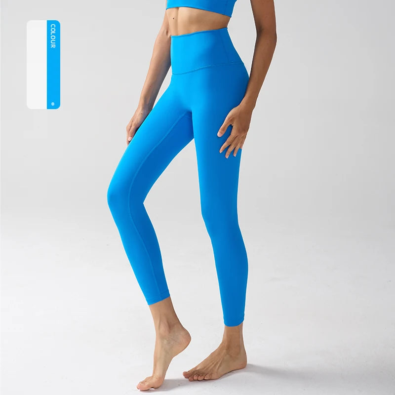 Une personne portant des leggings de sport bleu vif à taille haute, debout sur un fond gris clair.