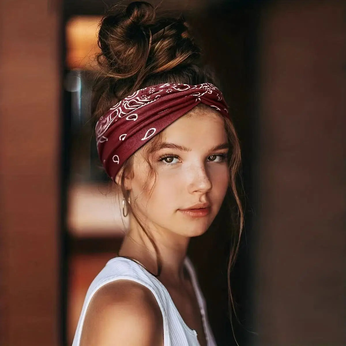 A young woman wearing a maroon bohemian print wide headband tied around her hair.