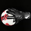 Black and white latex goalkeeper gloves with a wrist strap shown against a black background.